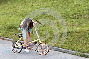 A beautiful young woman folds up and unfolds a bicycle. Convenient folding bike for travel and transportation