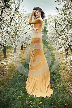 Beautiful young woman among fragrant apple trees