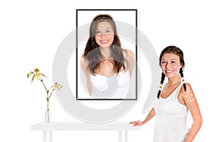 Beautiful young woman in front of a beauty portrait of herself