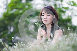 Beautiful young woman funning on grass with flowers