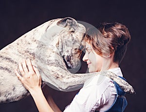 Beautiful young woman with a funny shaggy dog on a dark background. Love, care, friendship