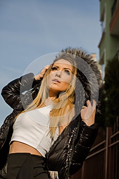 Beautiful young woman in fur hood posing in winter
