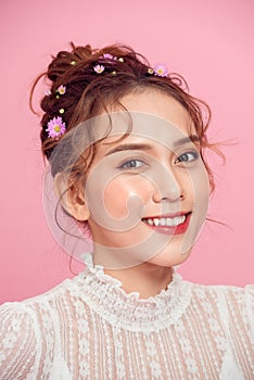 Beautiful young woman with gerber flower isolated on pink background