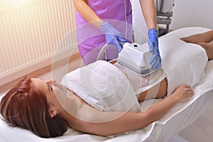 Beautiful young woman getting cryolipolyse treatment in cosmetic cabinet
