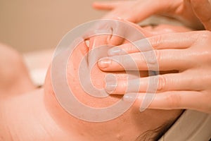 Beautiful young woman getting a face massage treatment at beauty salon