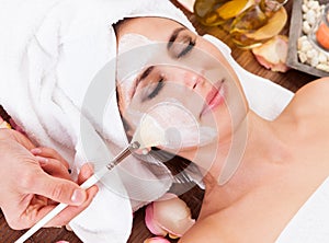 Beautiful young woman getting facial mask