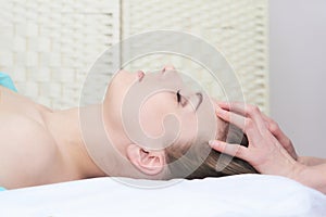 Beautiful young woman getting facial massage in the spa salon, close-up portrait, side view