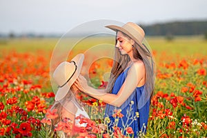 beautiful young woman with girl in straw hats in poppy field, happy family having fun in nature