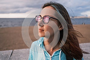 Beautiful young woman with glasses looks at the sunset.