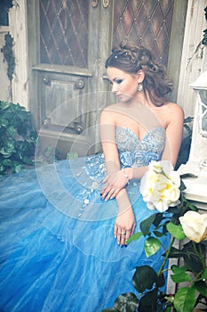 Beautiful young woman in gorgeous blue long dress like Cinderella with perfect make-up and hair style