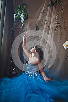 Beautiful young woman in gorgeous blue long dress like Cinderella with perfect make-up and hair style