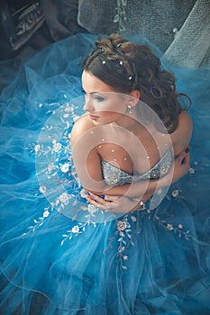 Beautiful young woman in gorgeous blue long dress like Cinderella with perfect make-up and hair style