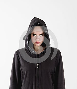 Beautiful young woman with green eyes, in black clothes with hood on a white background