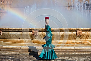 Beautiful young woman in a green frilly suit with a flower on her head. The woman is dancing flamenco and is in the most famous photo