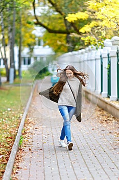 Beautiful young woman in green knitted cardigan with a hood walking in autumn park. Autumn fashin concept.