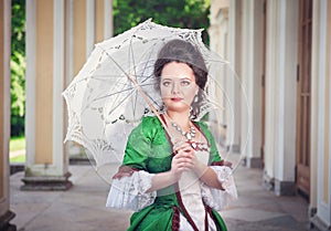 Beautiful young woman in green medieval dress with umbrella