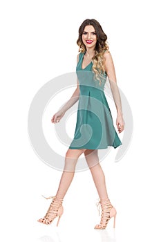 Beautiful Young Woman In Green Mini Dress And High Heels Is Walking And Smiling
