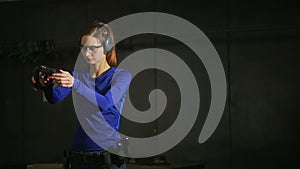 Beautiful young woman with the gun on an indoor shooting range. shoots a gun