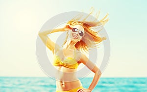 beautiful young woman with hair flying in the wind and sunglasses summer beach