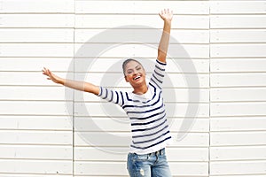 Beautiful young woman with happy expression and arms raised