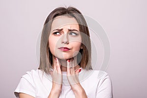 Beautiful young woman has a sore throat, close-up, isolated on a gray background