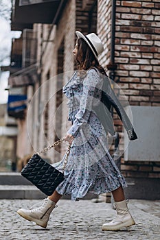 a beautiful young woman in a hat and a blue dress walks through the city. walk, shopping