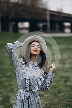 beautiful young woman in a hat and dress on the background of a field with flowers