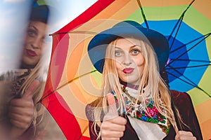 Beautiful young woman in hat holding umbrella and