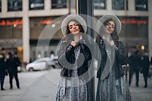 beautiful young woman in a hat and leather jacket near the mall. purchases. shopping