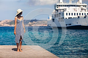 Beautiful young woman in hat relax on wooden pier on Sardinia beach