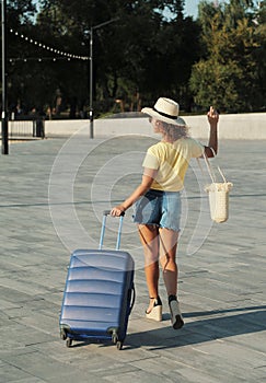 Beautiful young woman in hat with suitcase and wine glass waiting a ship for summer trip.