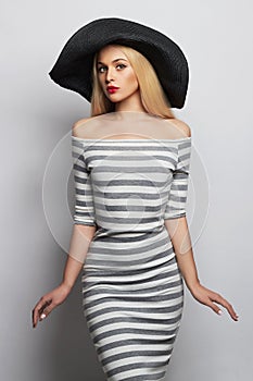 Beautiful young woman in hat. summer fashion girl in trendy striped dress