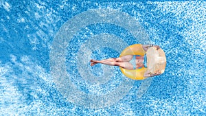 Beautiful young woman in hat in swimming pool aerial top view from above, young girl in bikini relaxes on inflatable ring