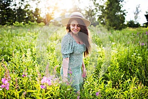 Beautiful young woman in a hat walks in a field