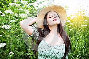 Beautiful young woman in hat among wildflowers