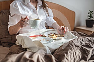 Woman have a romantic Breakfast in cozy morning bed. Coffee and word love from cookies. Surprise on Valentine`s day