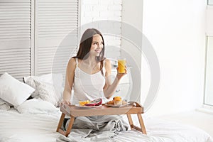Beautiful young woman having breakfast on bed at home photo