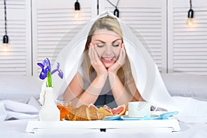 Beautiful young woman having breakfast in bed. Surprise from beloved husband. Celebrating a woman`s day, mother`s day.