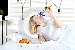 Beautiful young woman having breakfast in bed. Surprise from beloved husband. Celebrating a woman`s day, mother`s day.