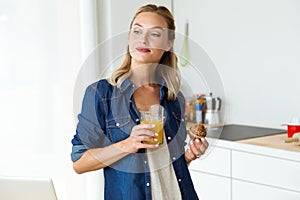 Beautiful young woman having breakfast in the kitchen.