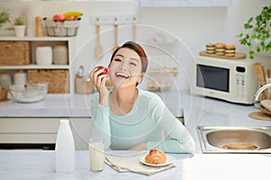 Beautiful young woman having breakfast in kitchen