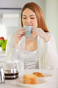 beautiful young woman having breakfast in kitchen