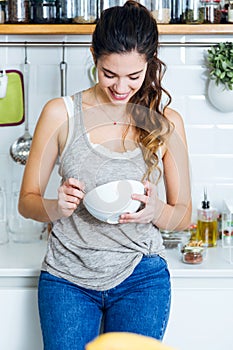 Beautiful young woman having breakfast in the kitchen.