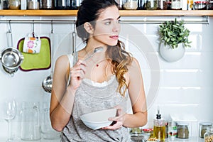 Beautiful young woman having breakfast in the kitchen.