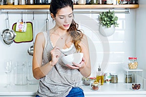 Beautiful young woman having breakfast in the kitchen.