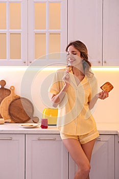 Beautiful young woman having breakfast in kitchen. Weekend morning