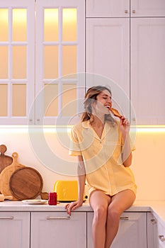 Beautiful young woman having breakfast in kitchen. Weekend morning