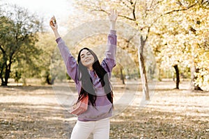 Beautiful young woman having fun, enjoying autumn weather in the park