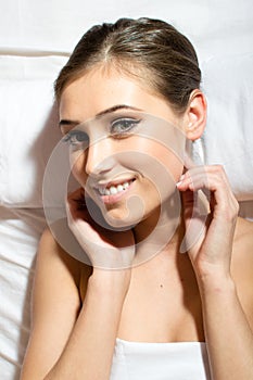 Beautiful young woman having fun relaxing lying on a massage table in towel happy smiling looking at camera closeup portrait