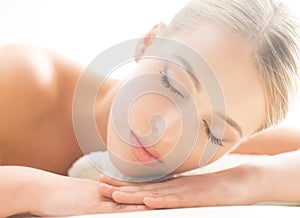 Beautiful young woman having leisure lying in a mat in spa